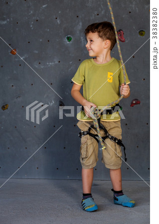 little boy standing near a climbing rock wall indoor. little boy standing near a climbing rock wall indoor. 38382380
