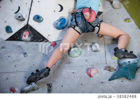 Teen girl climbing a rock wall indoor. 38382488