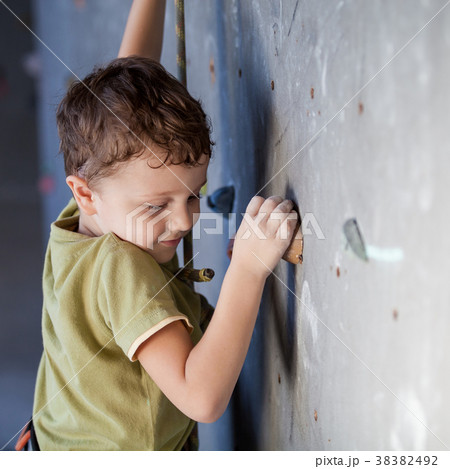little boy climbing a rock wall indoor. 38382492