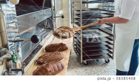 Woman in bakery putting bread on board 38385408