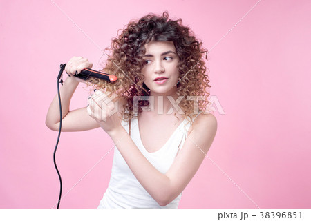 Beautiful young woman making curls with curling 38396851