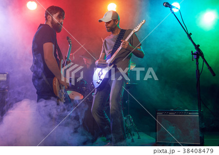 Rock band performs on stage. Guitarist, bass guitar and drums. 38408479