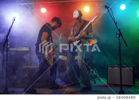 Rock band performs on stage. Guitarist, bass guitar and drums. 38408480
