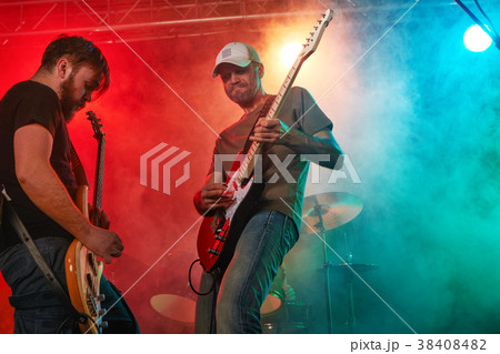 Rock band performs on stage. Guitarist, bass guitar and drums. 38408482