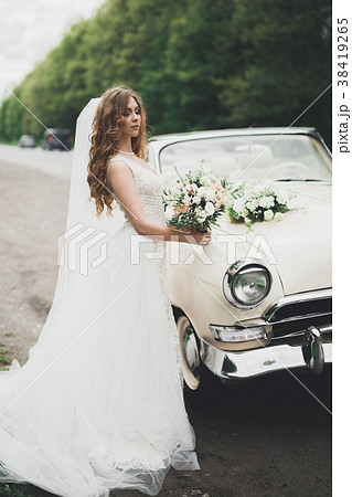 A beautiful bride posing near retro car outdoors 38419265