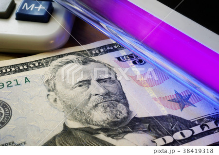 Dollar banknotes in a UV light. Counterfeit money. 38419318
