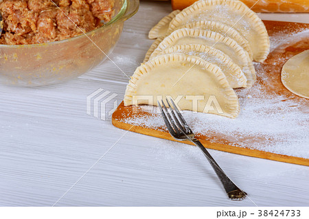 Not roasted cheburek with flour on a wooden board. Not roasted cheburek with flour on a wooden board. 38424733
