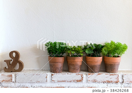 Four artificial plants in clay pot on wooden table 38426268