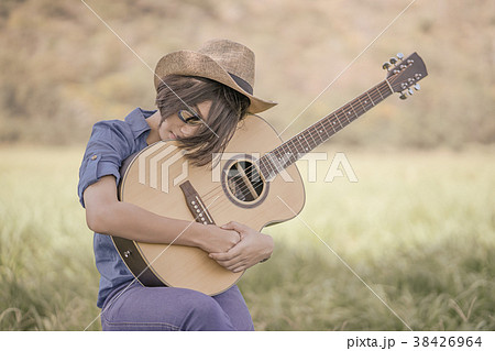 Women short hair wear hat and sunglasses sit playing guitar in g 38426964