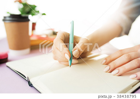 The female hands holding pen. The trendy pink desk The female hands holding pen. The trendy pink desk 38438795