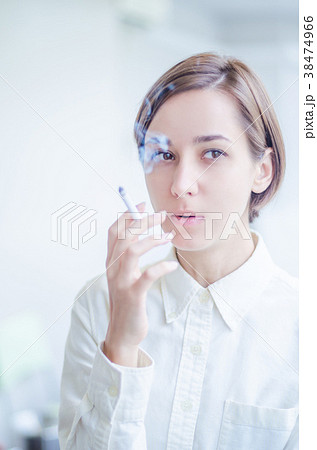 タバコを吸う笑顔の若い女性の写真素材