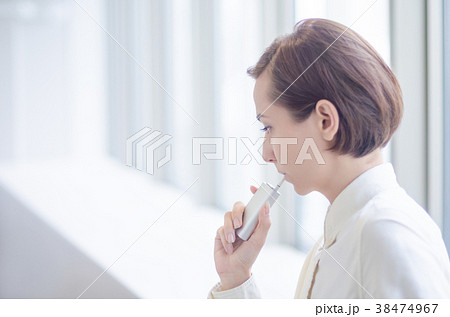 加熱式タバコを吸うショートヘアーの女性の写真素材