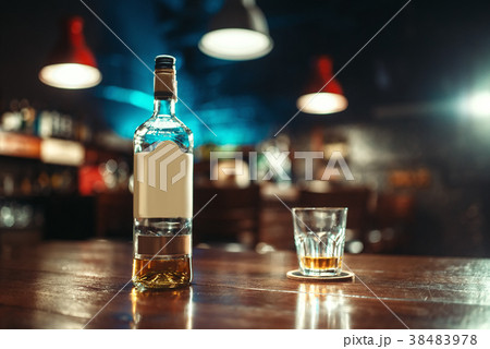 Bottle of alcohol and glass on bar counter closeup 38483978