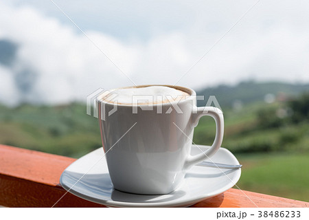 Close up white cup of hot coffee on balcony edge  38486233