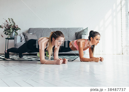 Two fit women doing plank exercise on floor at Two fit women doing plank exercise on floor at 38487737