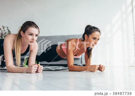 Two fit women standing in plank position on floor 38487739