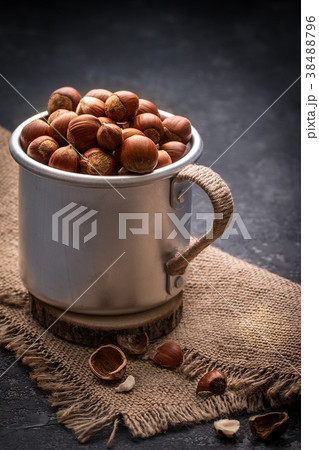 Full mug of hazelnuts with peel  on dark  table 38488796