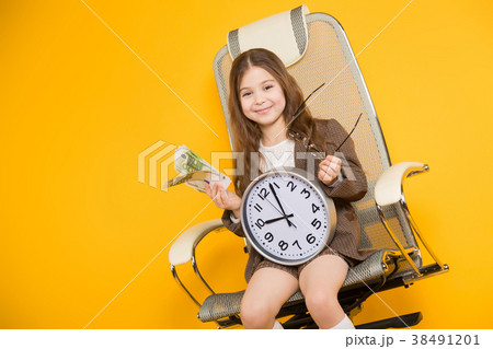 Little brunette girl with clocks and cash in chair 38491201