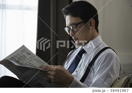 英字新聞を読むお洒落なビジネスマンの写真素材