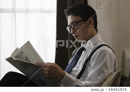 英字新聞を読むお洒落なビジネスマンの写真素材