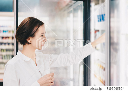 店舗の冷蔵庫から飲み物を選ぶ女性 38496594