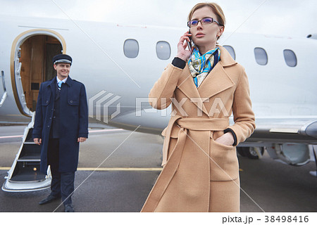Calm female telling by mobile near airplane Calm female telling by mobile near airplane 38498416