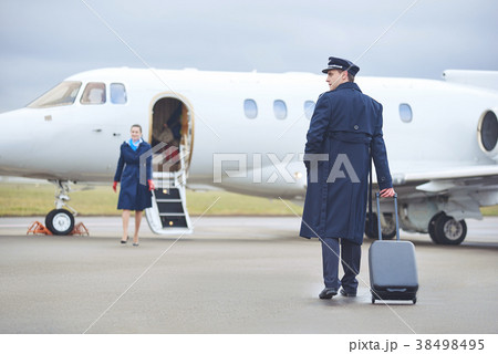 Beaming pilot walking to aircraft Beaming pilot walking to aircraft 38498495