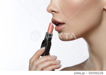 Young woman putting lipstick on mouth Young woman putting lipstick on mouth 38500226