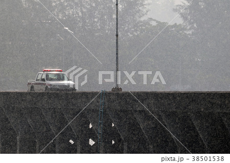 Police cars running on the bridge while heavy rain 38501538