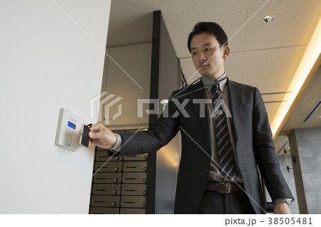 IDカードをかざしてドアロックを解除するビジネスマン IDカードをかざしてドアロックを解除するビジネスマン 38505481