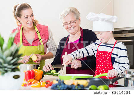 Granny, mum and son talking while cooking in 38514581