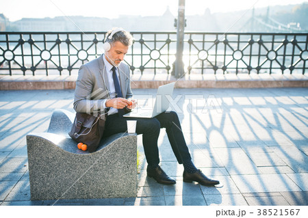 Mature businessman with laptop in a city. Mature businessman with laptop in a city. 38521567