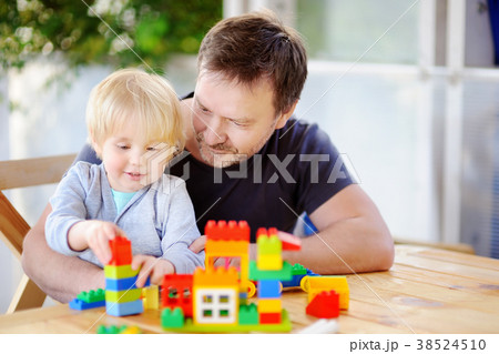 Little boy with his father playing with colorful plastic blocks at home Little boy with his father playing with colorful plastic blocks at home 38524510