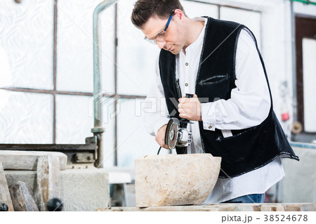 Stonemason cutting marble with angle grinder 38524678