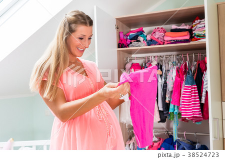 Pregnant woman in front of wardrobe in childs room 38524723