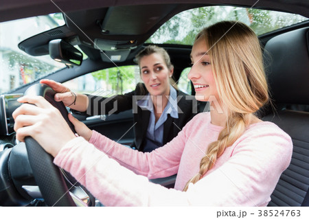 Student on wheel of car in driving lesson with her Student on wheel of car in driving lesson with her 38524763