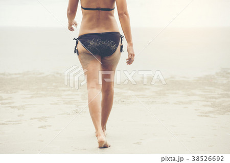 Woman brown bikini walking on white sand beach 38526692