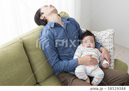 赤ちゃんを抱いて寝落ちするパパの写真素材