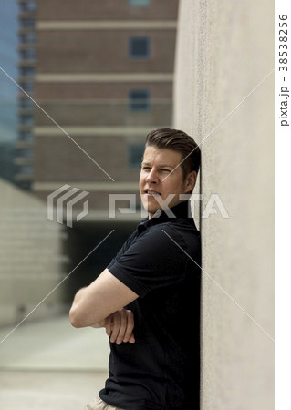 Man Leaning on Beige Outdoor Wall Man Leaning on Beige Outdoor Wall 38538256