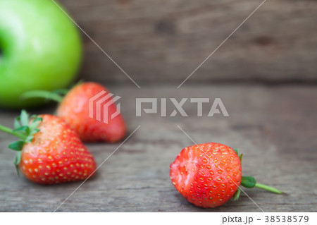 Close up of bitten strawberry on wooden table Close up of bitten strawberry on wooden table 38538579