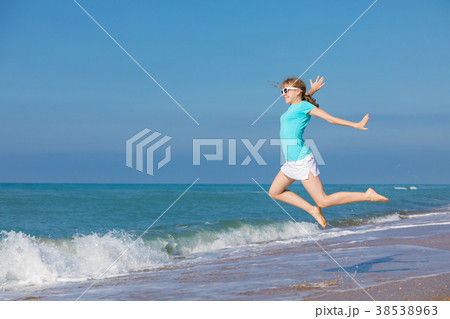 teen girl jumping on the beach at blue sea shore in summer vacat 38538963