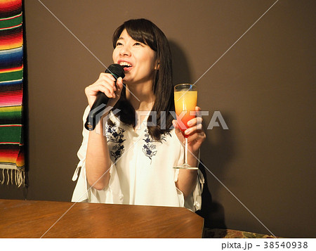 カクテルを持ってカラオケで歌う女性 38540938