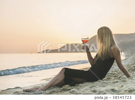 Young woman enjoying glass of rose wine on beach 38545723