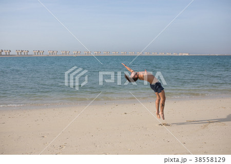 Young man doing somersault on the beach. 38558129