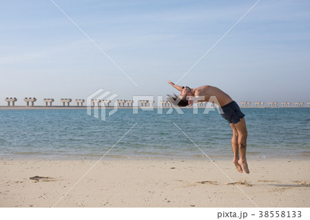 Young man doing somersault on the beach. Young man doing somersault on the beach. 38558133