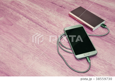 Smartphone charging with power bank on wood Smartphone charging with power bank on wood 38559730