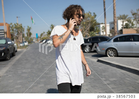 Man in a white T-shirt smokes and speaks on the 38567503