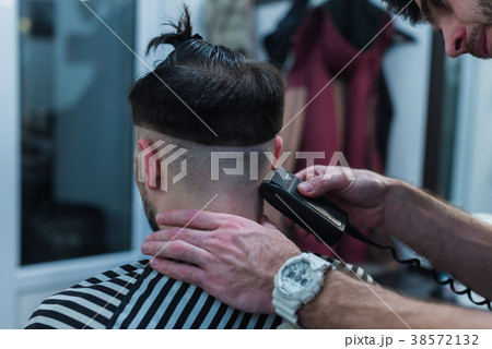 Male Barber Giving Client Haircut In barber shop 38572132
