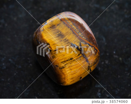 polished tiger-eye gem stone on dark background polished tiger-eye gem stone on dark background 38574060