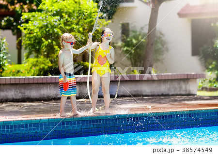 Kids play with water hose at swimming pool. Kids play with water hose at swimming pool. 38574549
